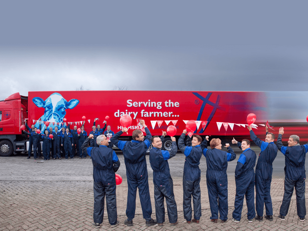 Foto van het personeel van Heemskerk in overall, op de achtergrond een Heemskerk vrachtwagen.